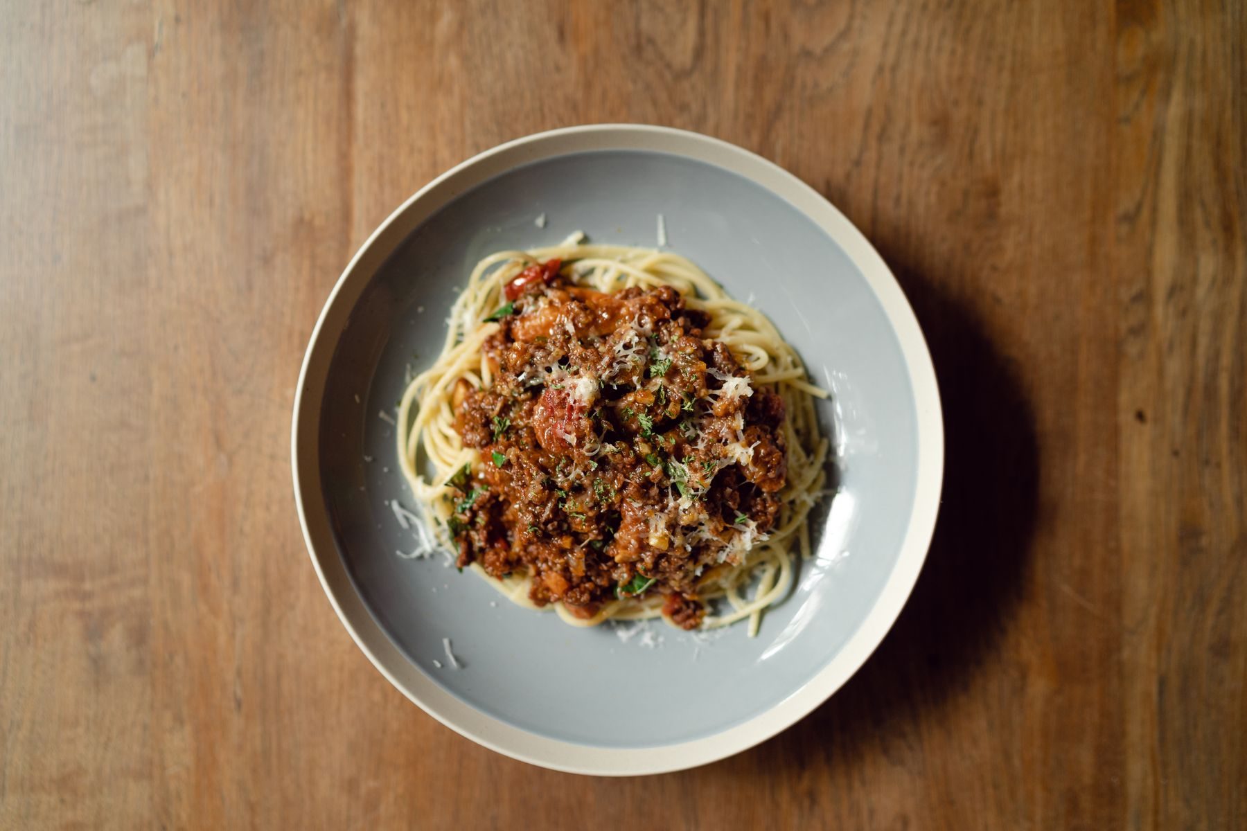 A plate of spaghetti bolognese shot from above on dark wood — the 11 PM plate