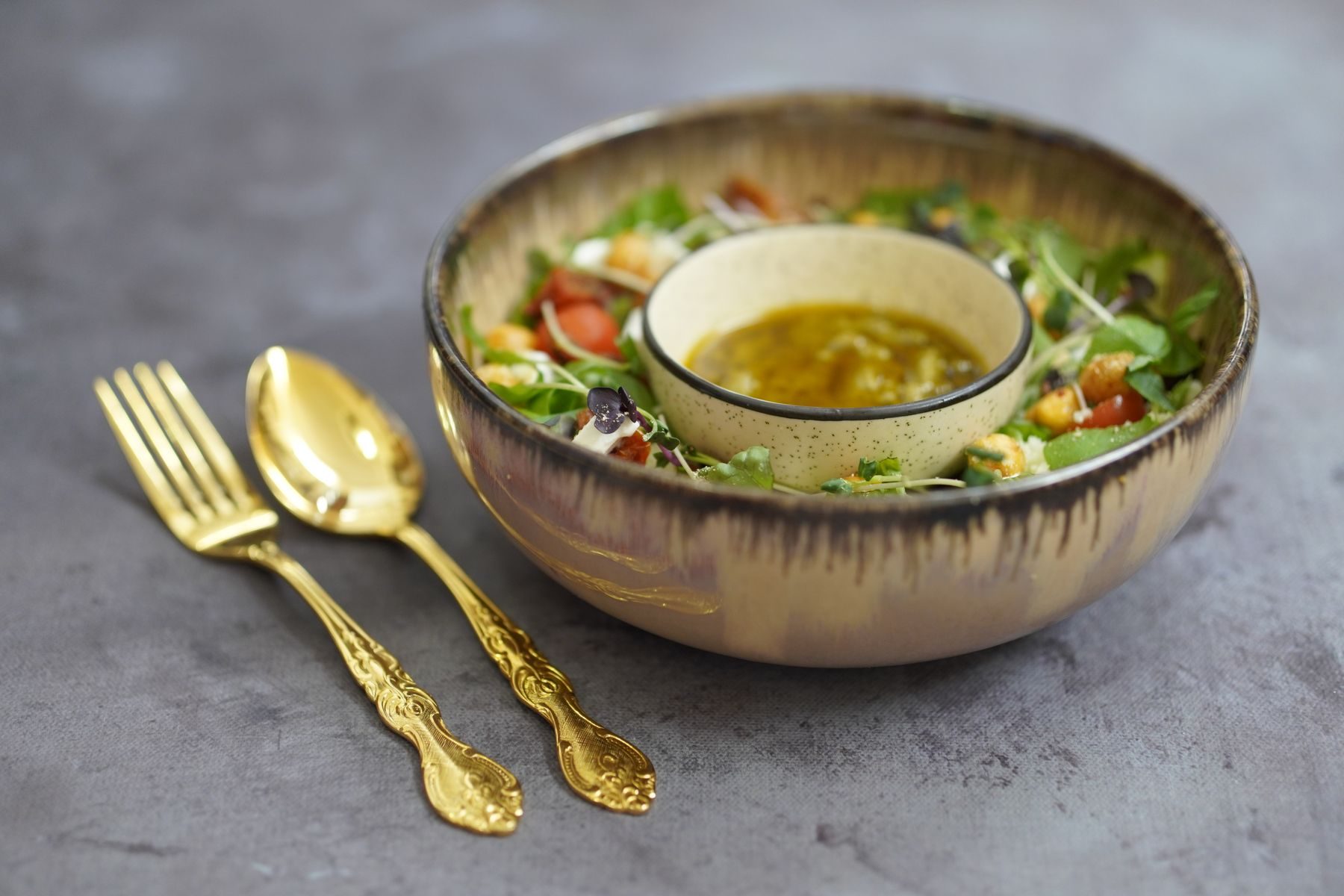 A green salad ringed around a small bowl of golden vinaigrette